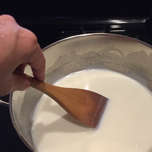 Homemade yogurt, heating and stirring milk.